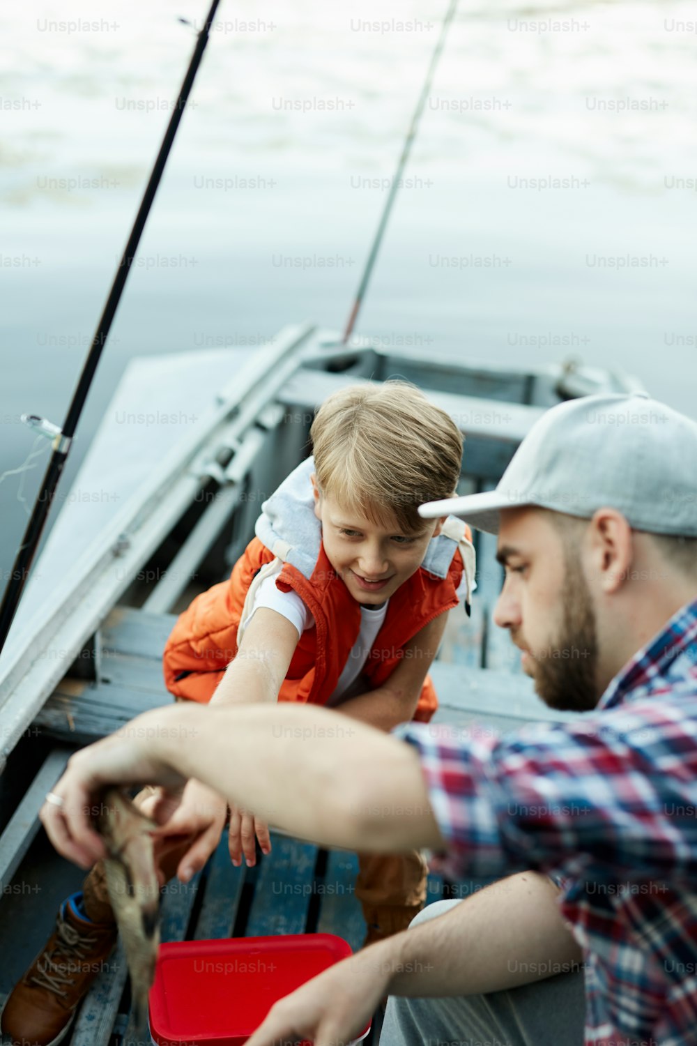 Padre e hijo pescando un pez mientras pescaban en el bote en el lago