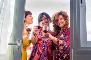 집에서 함께 와인을 마시는 세 명의 백인 젊은 여성을 위한 축하와 행복의 시간. 창문에서 백라이트가있는 우정과 파티 시간.
