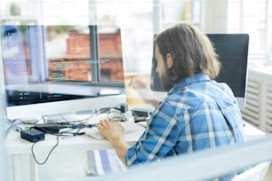Junger Programmierer, der neue Software testet oder Daten vor dem Computerbildschirm dekodiert