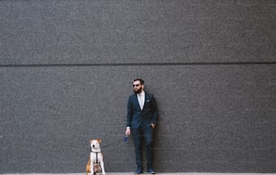 通りで犬を散歩させるビジネスマン。親友が歩いている。ハンサムなビジネスマンのヒップスターの散歩犬。