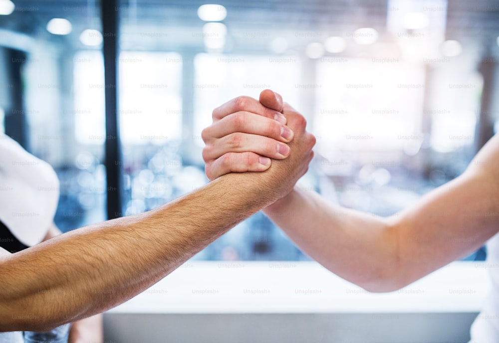 A friendly handshake of two young unrecognizable men in gym gym. A close-up.