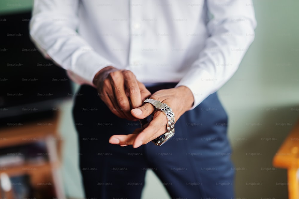 Gros plan d’un homme mettant une montre sur sa main.