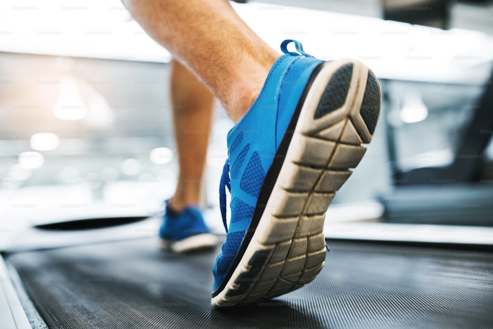 Close-up of feet of young man in gym running on treadmill.