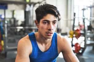 Un primer plano de un joven hispano guapo en el gimnasio, descansando después de un ejercicio.