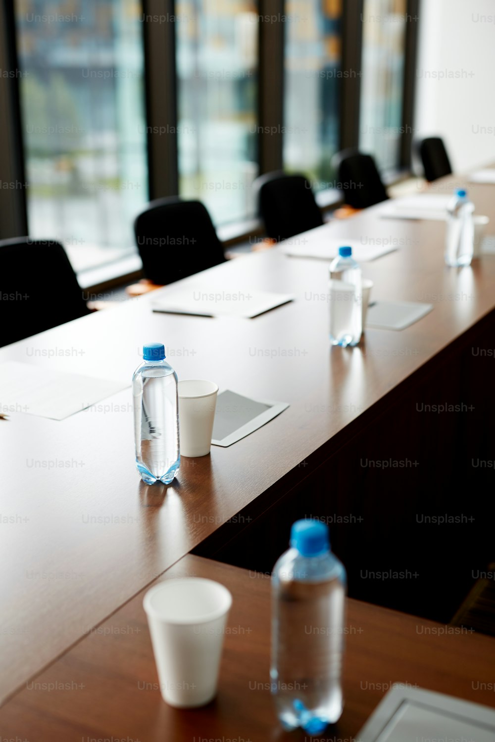 Background image of empty conference tables with water bottles and sheets of paper prepared for big important business meeting, copy space