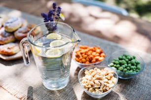 Nahaufnahme eines Tisches für eine Gartenparty oder Feier draußen. Wasser in einem Krug, Nüsse und andere herzhafte Snacks auf dem Tisch.