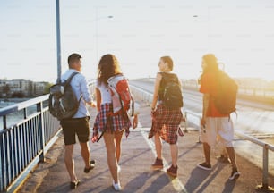 Four young student tourists walking over the bridge on a hot summer day.