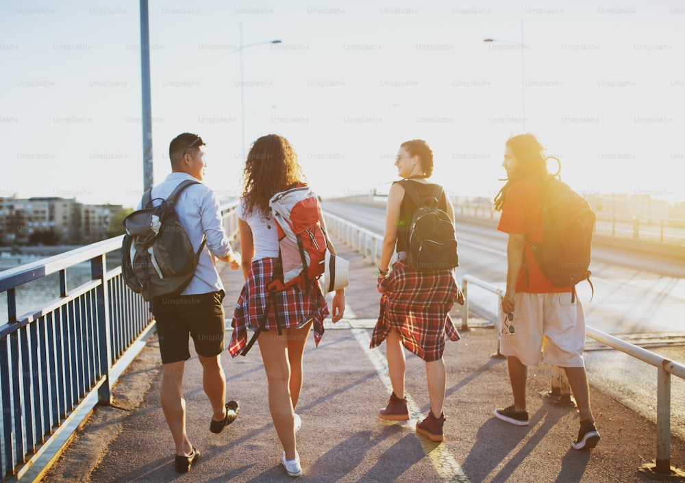 Four young student tourists walking over the bridge on a hot summer day.