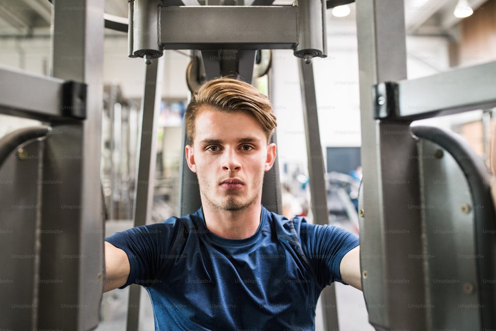 Young handsome fit man working out, using weight machine.