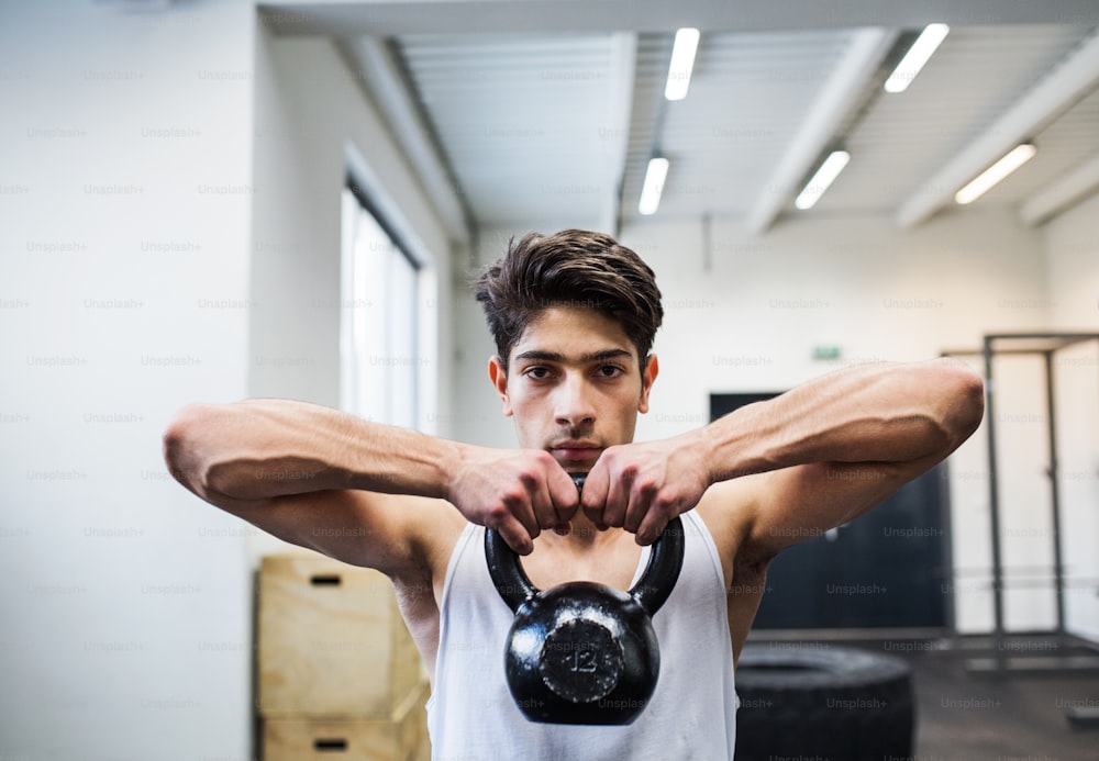 Fitter hispanischer Mann, der Krafttraining macht und Kettlebell im Fitnessstudio hebt.