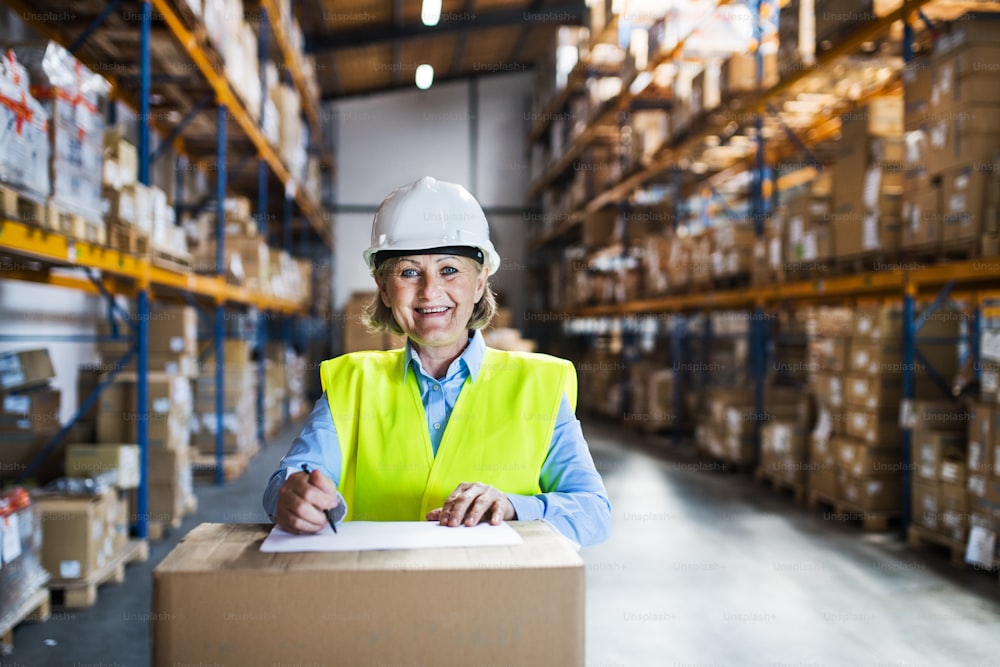 A senior woman worker or supervisor controlling stock in a warehouse.