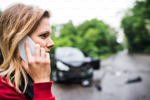 Um close-up de uma jovem mulher ao telefone ao lado do carro danificado após um acidente de carro. Espaço de cópia.