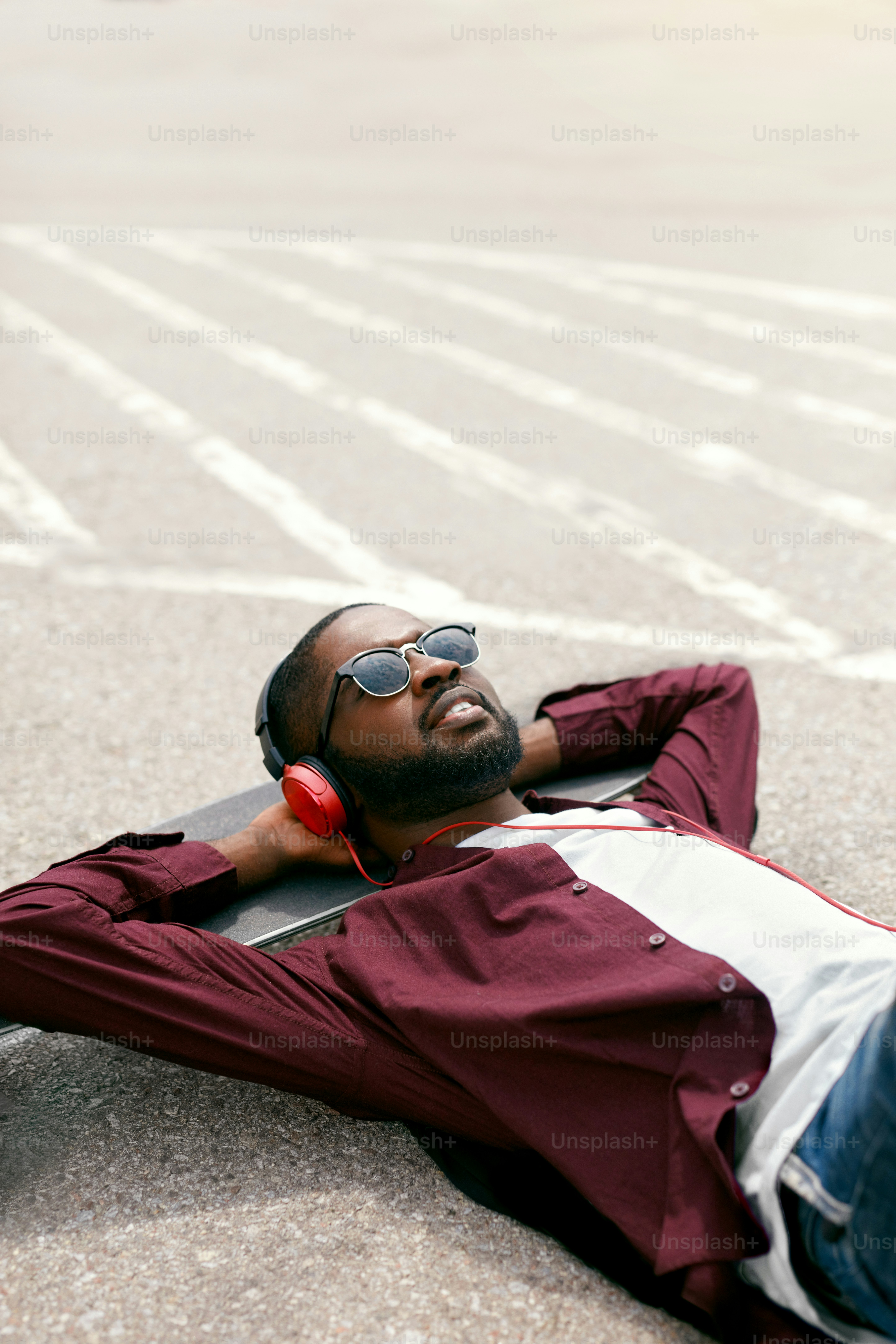 Fashion. Black Man Listening Music In Headphones On Street, Lying On Longboard. High Resolution