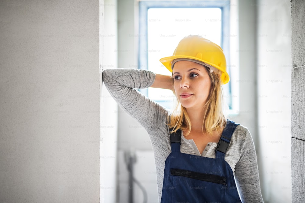 Portrait of a female worker on the construction site. Close-up of a beautiful young woman with a yellow helmet. Copy space.