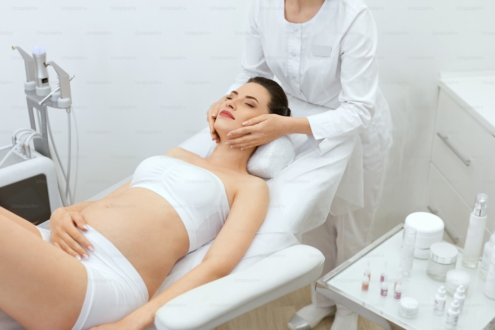 Face Skin Massage. Pregnant Woman At Cosmetology Clinic. Beautiful Female Getting Facial Massaging At Cosmetologist. High Resolution