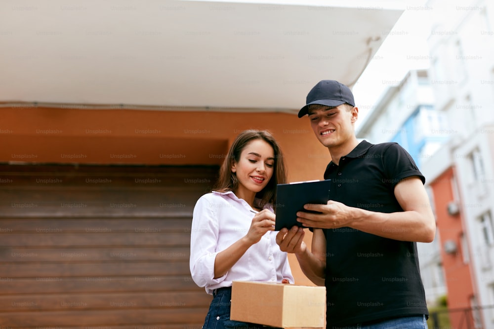 Delivery Courier. Man Delivering Package To Woman. Client Signing Delivery Documents. High Resolution