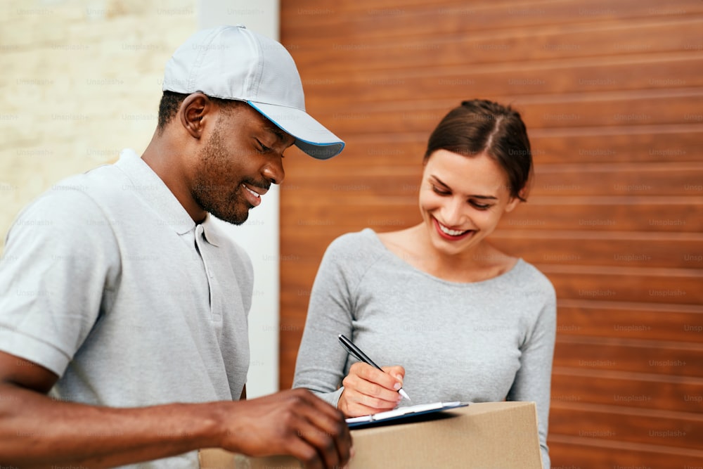 Courier Delivery Service. Man Delivering Package To Woman, Signing Documents On Box. High Resolution