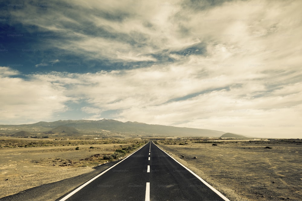 long way black asphalt road in the middle of the desert. travel and discover lost places concept for wanderlust people. straight white lines and infinite journey feeling in the nature