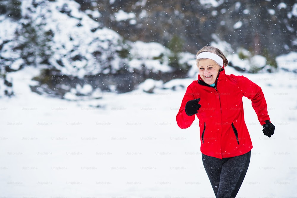 Senior woman jogging outside in winter nature. Copy space.