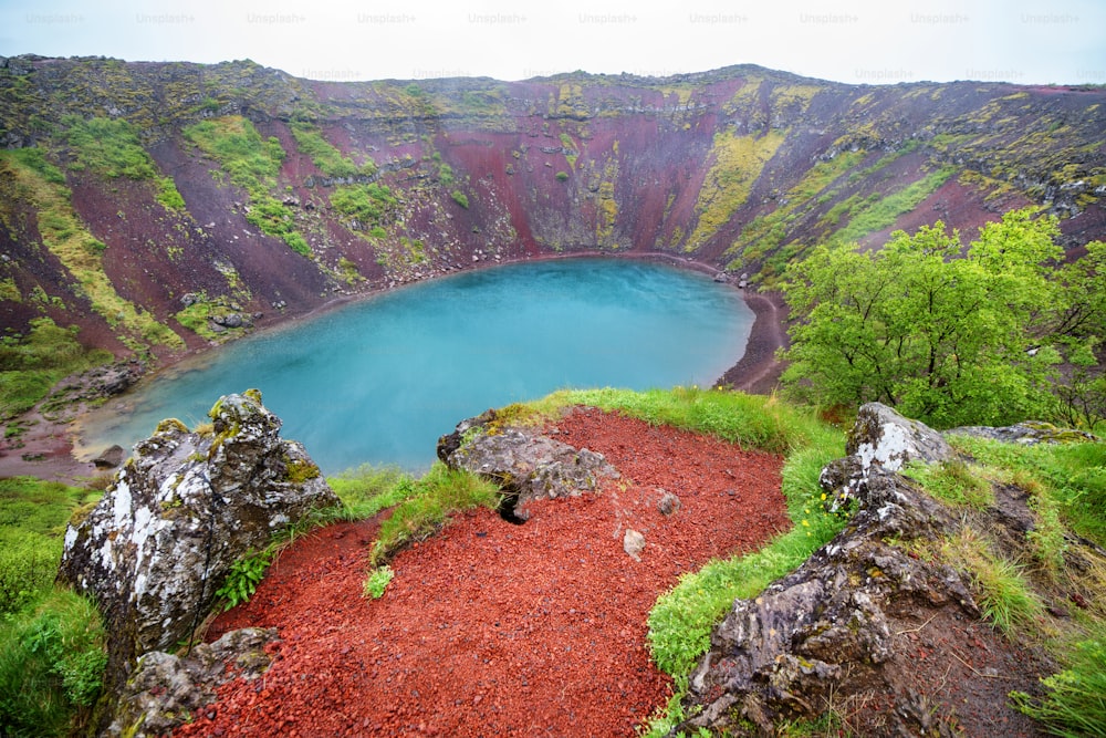 Cratera do vulcão com um lago azul-turquesa dentro, paisagem da Islândia.