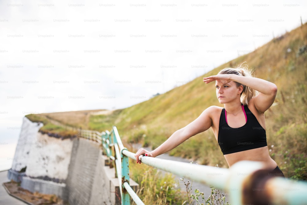 Jovem atleta mulher corredora em activewear preto em pé fora na natureza, descansando. Espaço de cópia.