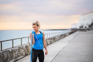 Giovane corridore donna sportiva che fa esercizio con elastici all'aperto su una spiaggia in natura. Copia spazio.