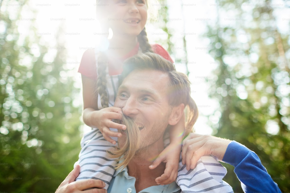 Little daughter having fun with dad during chill in the forest on sunny day