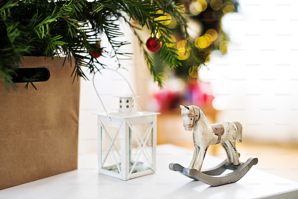 Un primo piano di una lanterna e di un cavallo a dondolo su un tavolo di casa nel periodo natalizio.