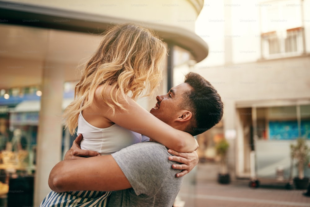 Young couple embracing and looking into each other's eyes while sharing a romantic moment on a city street