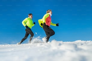 Coppia di corridori anziani che corrono nella natura invernale nella neve. Copia spazio.