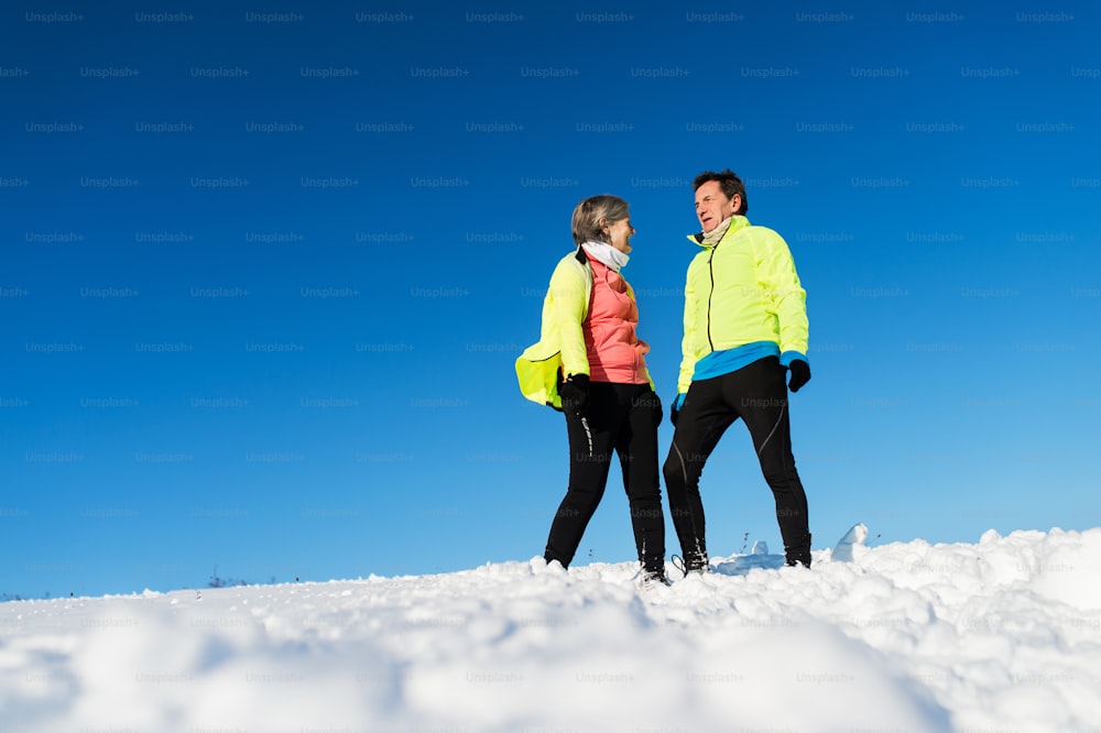 Senior couple runners resting in winter nature in snow. Copy space.