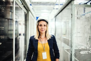 A portrait of a young industrial woman engineer standing in a factory.