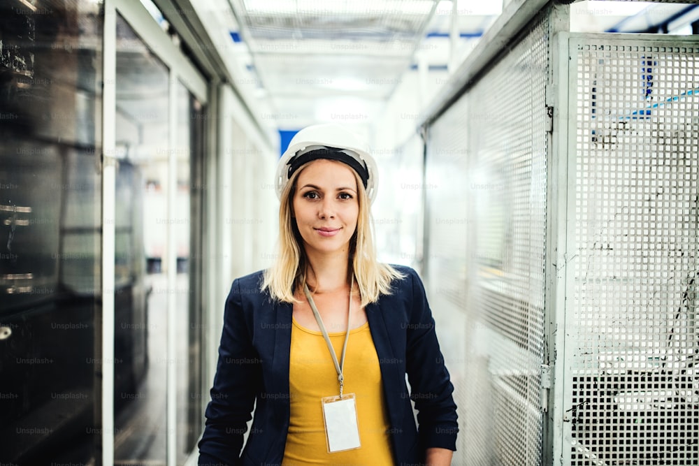 A portrait of a young industrial woman engineer standing in a factory.