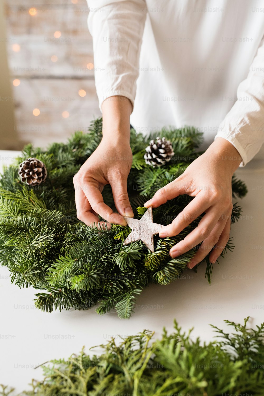 花輪を飾る見分けのつかない女性の手。クリスマスの構図。