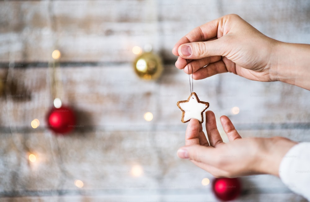Mano femenina sosteniendo adornos navideños. Una galleta en forma de estrella en una cuerda. Espacio de copia.