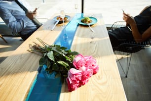 신선한 분홍색 장미가 테이블에 음식과 배경에 가제트에 중독된 커플