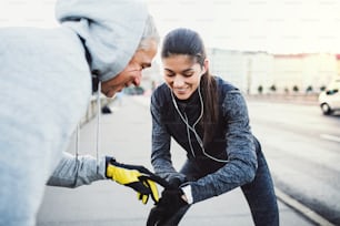 A fit sporty couple runners measuring time on a smartwatch outdoors on the streets of Prague city.