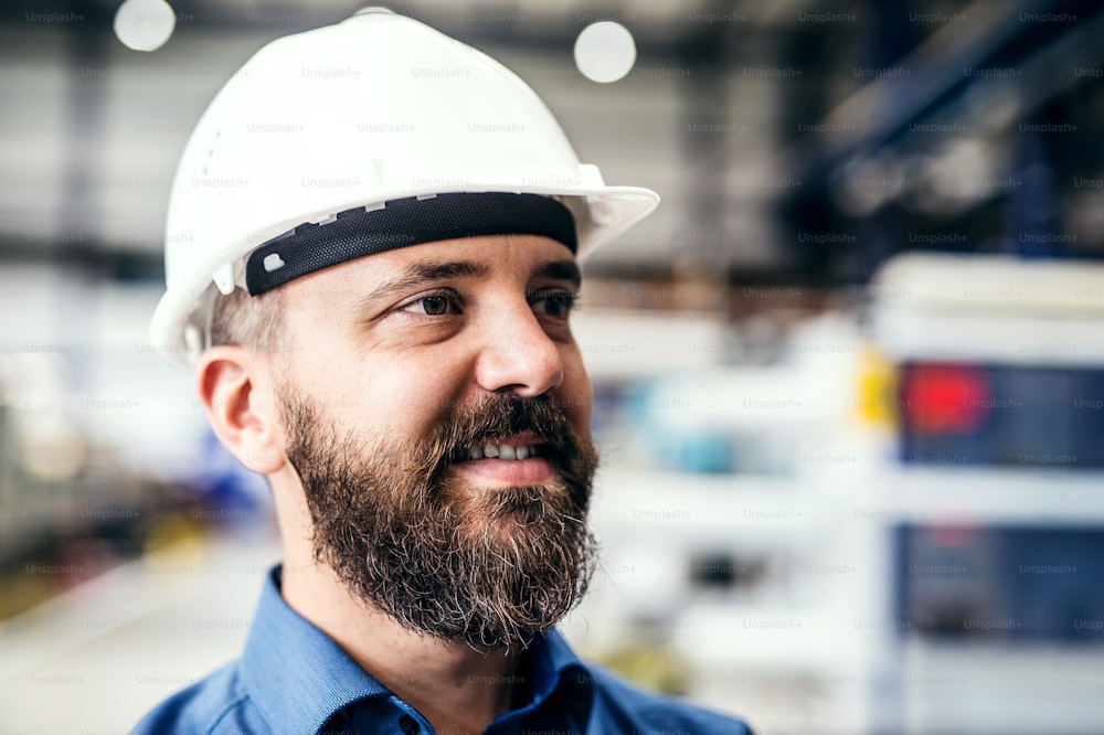 A portrait of a happy industrial man engineer with helmet in a factory.
