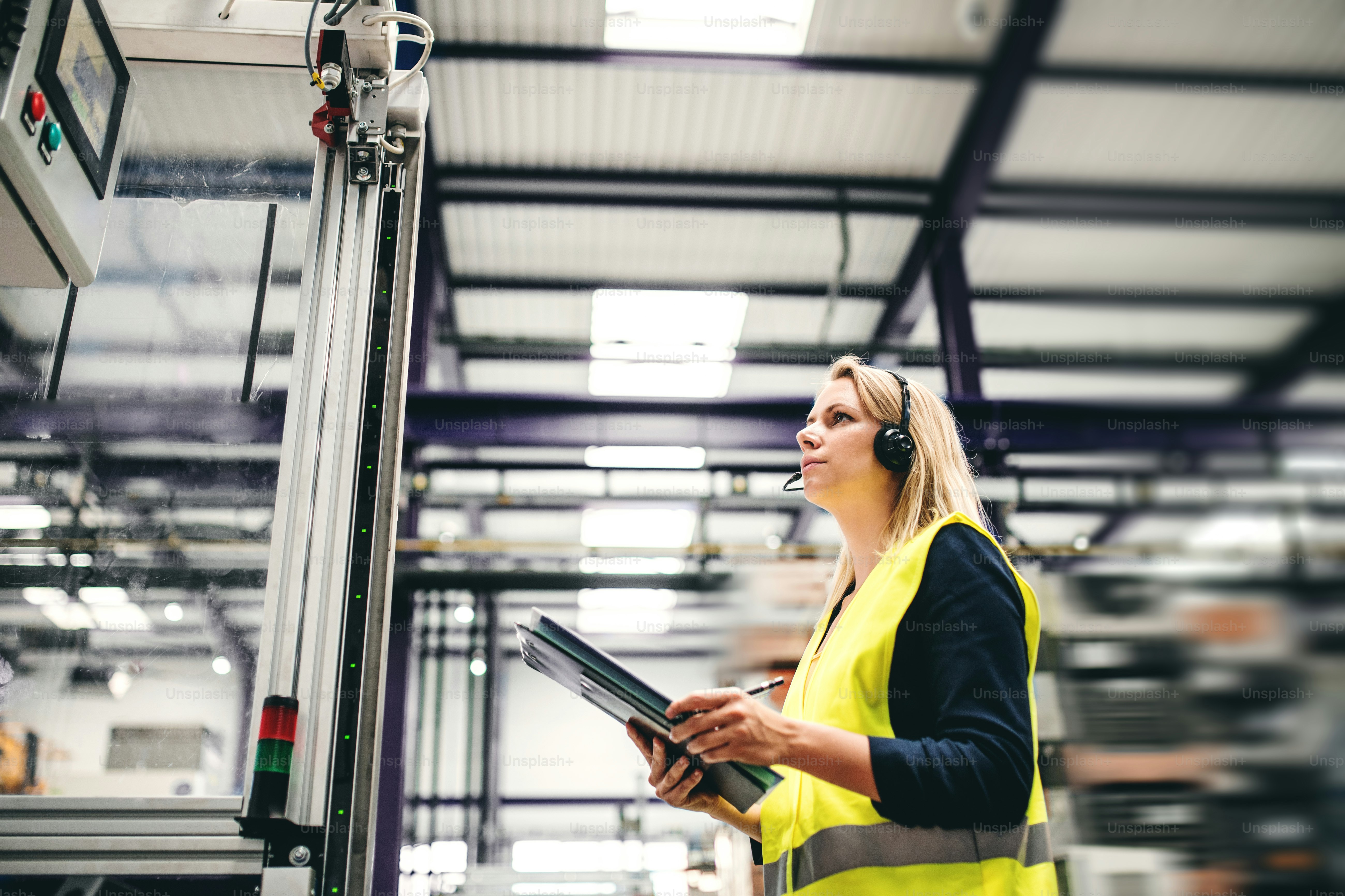 A portrait of a happy industrial woman engineer standing in a factory ...