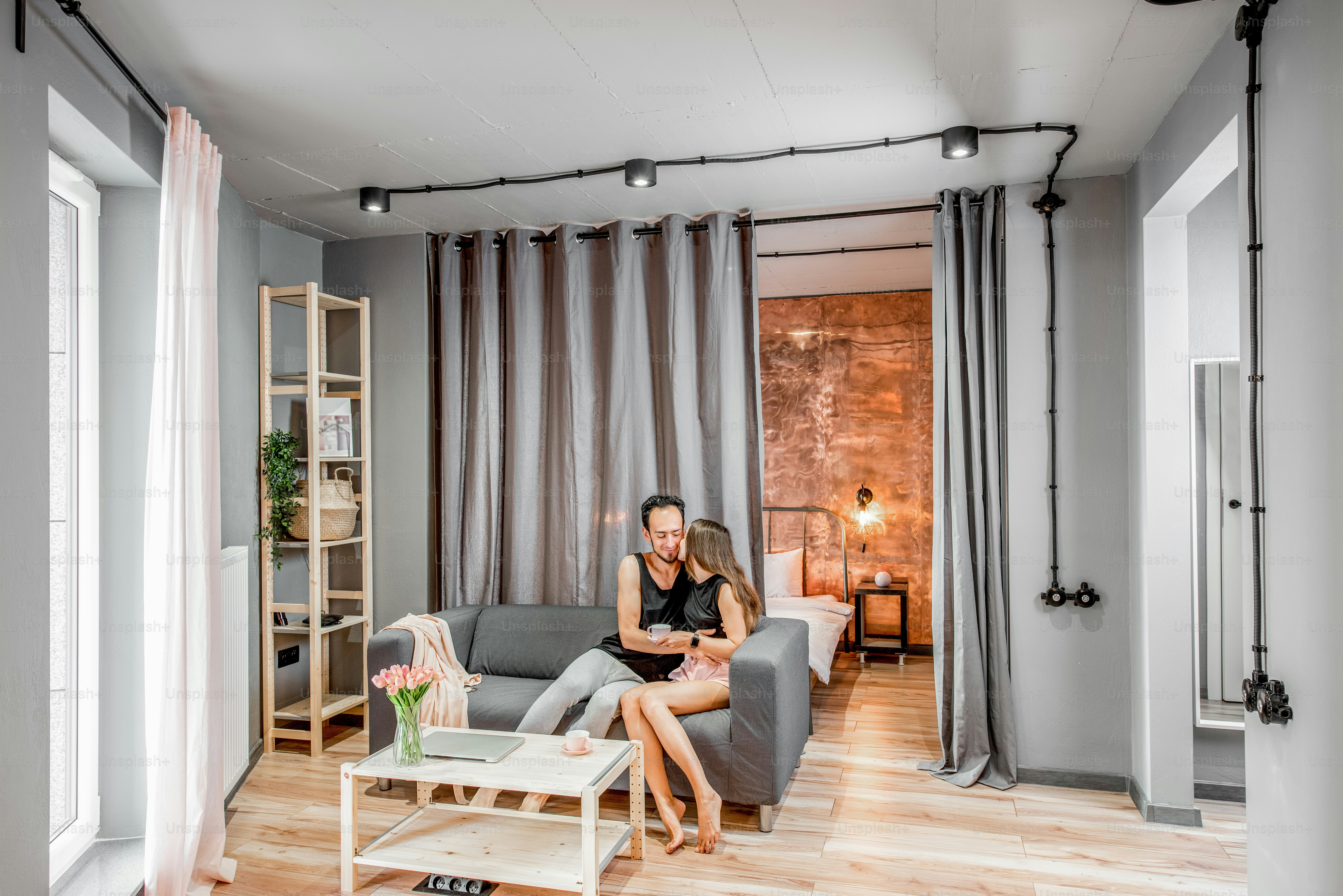 Modern living room with young lovely couple on the couch at their apartment