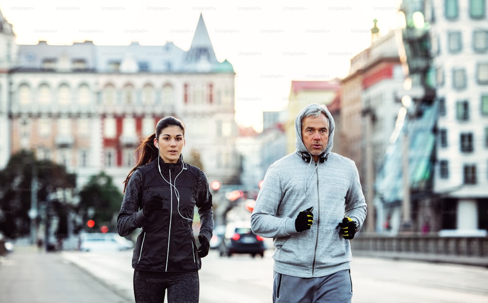 A fit sporty couple with headphones running outdoors on the streets of Prague city, Czech Republic.