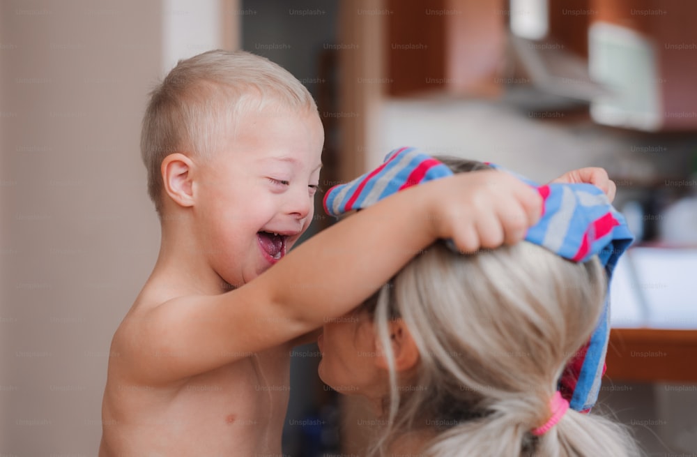 A laughing handicapped down syndrome child with his unrecognizable mother indoors having fun.