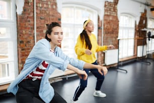 Junge aktive Frau und ihre Mitschülerin lernen Hip-Hop-Tanzen im modernen Studio