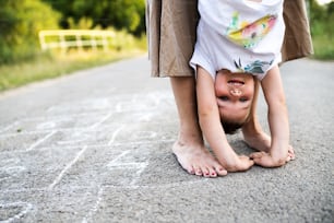 여름날 공원의 도로에서 작은 아들을 거꾸로 안고 있는 알아볼 수 없는 맨발의 어머니.