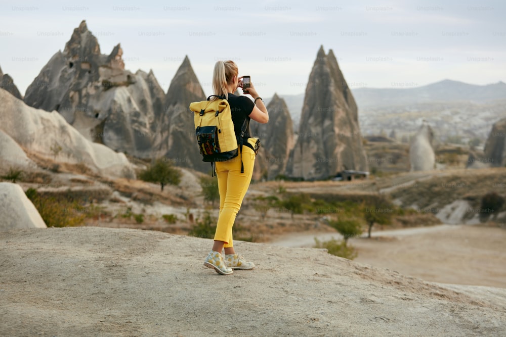 여행하는 여자, 자연 풍경의 전화로 사진을 찍는. 배낭을 메고 사진을 만드는 여성. 고해상도