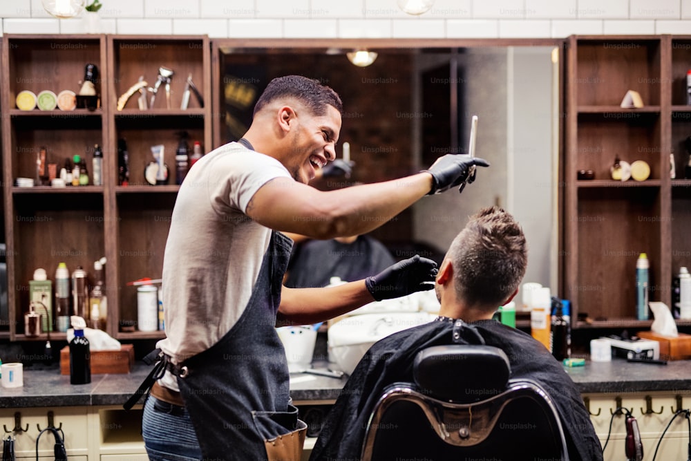 理髪店のハイドレッサーとヘアスタイリストを訪れる男性のクライアントの後ろ姿ショット。