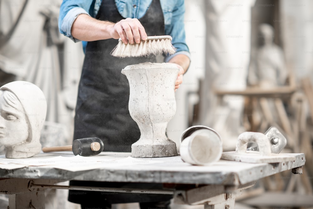 Homme travaillant avec un vase en pierre sur le lieu de travail dans l’ancien atelier. Vue rapprochée sans visage