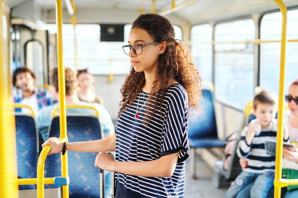 Young woman standing and riding in the public transport and looking through window.