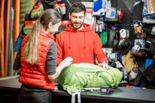 Young woman buying some sports goods standing with salesman at the counter of the shop