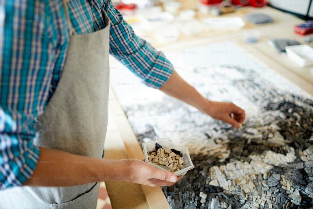 Mittelteilporträt eines nicht erkennbaren Handwerkers, der Fliesen auslegt, während er Mosaik im Werkstattatelier erstellt, Kopierraum